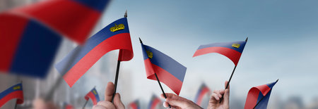 Liechtenstein flags in their hands on a blurred urban backgroundの写真素材