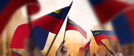 Liechtenstein flags in their hands on a blurred urban backgroundの写真素材
