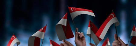 Singapore flags in their hands on a blurred urban backgroundの写真素材