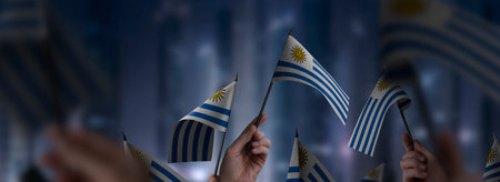 Uruguay flags in their hands on a blurred urban backgroundの写真素材