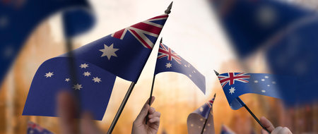 Australia flags in their hands on a blurred urban background. The photo illustration was created without the use of artificial intelligence, only using Photoshop.の写真素材