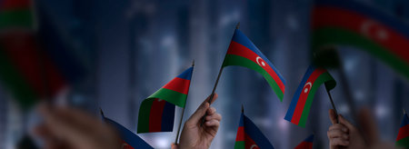 Azerbaijan flags in their hands on a blurred urban background. The photo illustration was created...