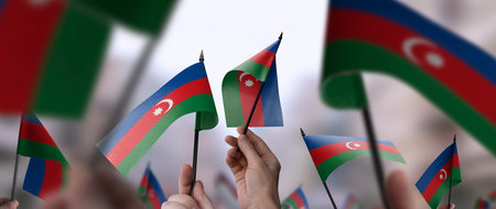 Azerbaijan flags in their hands on a blurred urban backgroundの写真素材