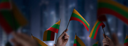 Lithuania flags in their hands on a blurred urban backgroundの写真素材