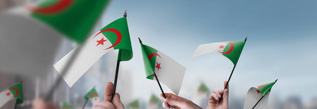 Algeria flags in their hands on a blurred urban backgroundの写真素材