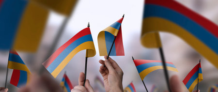 Armenia flags in their hands on a blurred urban backgroundの写真素材
