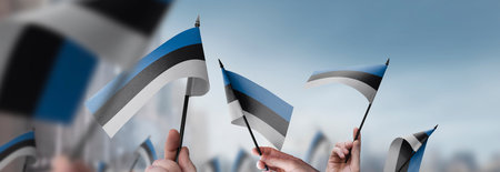 Estonia flags in their hands on a blurred urban background