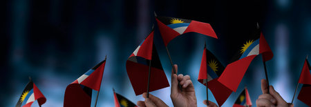 Antigua and Barbuda flags in their hands on a blurred urban backgroundの写真素材