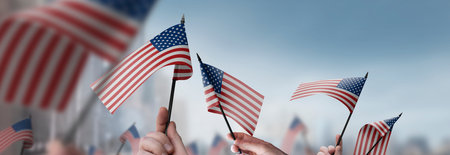 USA flags in their hands on a blurred urban backgroundの写真素材