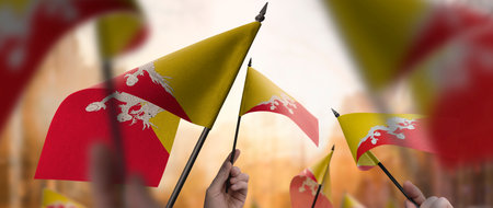 Bhutan flags in their hands on a blurred urban backgroundの写真素材