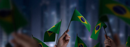 Brazil flags in their hands on a blurred urban backgroundの写真素材