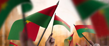 Burkina Faso flags in their hands on a blurred urban backgroundの写真素材