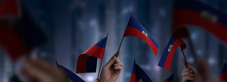 Haiti flags in their hands on a blurred urban background