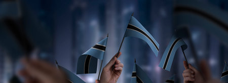 Botswana flags in their hands on a blurred urban backgroundの写真素材