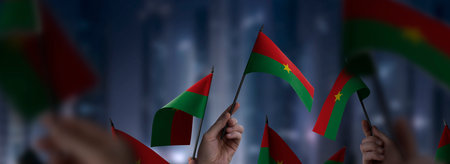 Burkina Faso flags in their hands on a blurred urban backgroundの写真素材