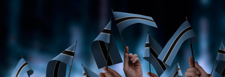 Botswana flags in their hands on a blurred urban backgroundの写真素材