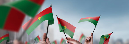 Burkina Faso flags in their hands on a blurred urban backgroundの写真素材