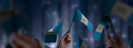 Guatemala flags in their hands on a blurred urban background. The photo illustration was created without the use of artificial intelligence, only using Photoshop.の写真素材