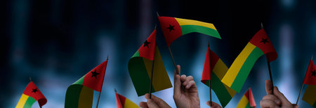 Guinea Bissau flags in their hands on a blurred urban background. The photo illustration was created without the use of artificial intelligence, only using Photoshop.の写真素材