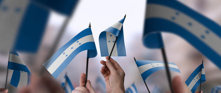 Honduras flags in their hands on a blurred urban background. The photo illustration was created without the use of artificial intelligence, only using Photoshop.の写真素材
