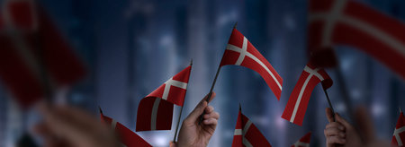 Denmark flags in their hands on a blurred urban background. The photo illustration was created without the use of artificial intelligence, only using Photoshop.の写真素材