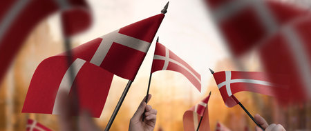 Denmark flags in their hands on a blurred urban background. The photo illustration was created without the use of artificial intelligence, only using Photoshop.の写真素材