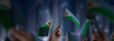 Djibouti flags in their hands on a blurred urban backgroundの写真素材