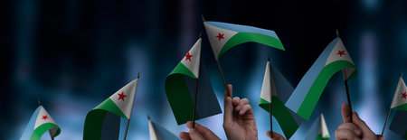 Djibouti flags in their hands on a blurred urban backgroundの写真素材