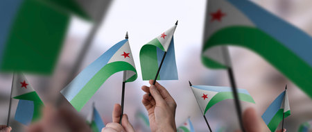 Djibouti flags in their hands on a blurred urban backgroundの写真素材