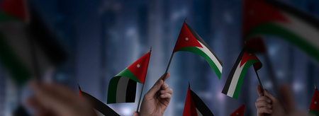 Jordan flags in their hands on a blurred urban backgroundの写真素材