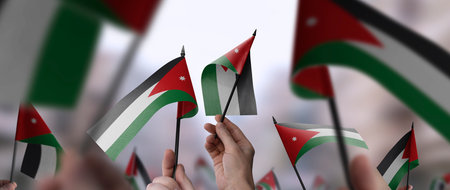 Jordan flags in their hands on a blurred urban backgroundの写真素材