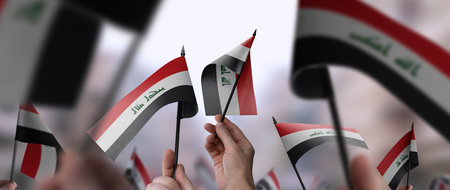 Iraq flags in their hands on a blurred urban backgroundの写真素材
