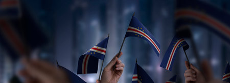 Cape Verde flags in their hands on a blurred urban background