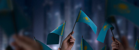 Kazakhstan flags in their hands on a blurred urban background