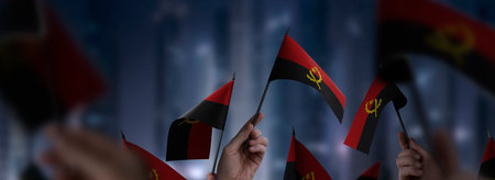 Angola flags in their hands on a blurred urban backgroundの写真素材