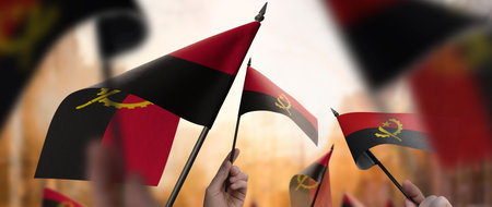 Angola flags in their hands on a blurred urban backgroundの写真素材