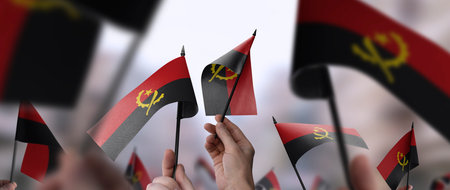 Angola flags in their hands on a blurred urban backgroundの写真素材