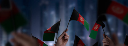 Afghanistan flags in their hands on a blurred urban backgroundの写真素材