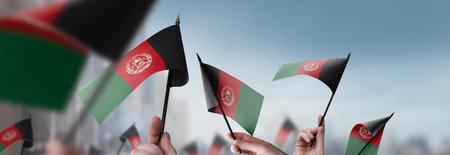 Afghanistan flags in their hands on a blurred urban backgroundの写真素材