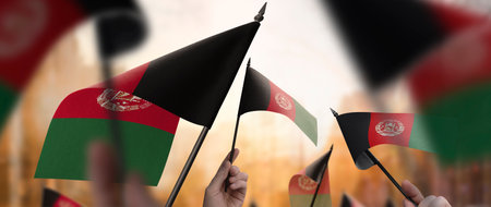 Afghanistan flags in their hands on a blurred urban backgroundの写真素材