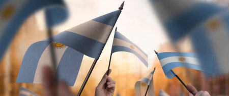 Argentina flags in their hands on a blurred urban backgroundの写真素材