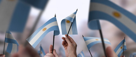 Argentina flags in their hands on a blurred urban backgroundの写真素材