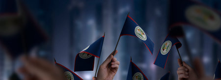 Belize flags in their hands on a blurred urban background