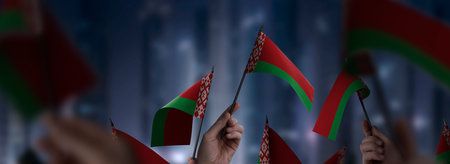 Belarus flags in their hands on a blurred urban backgroundの写真素材