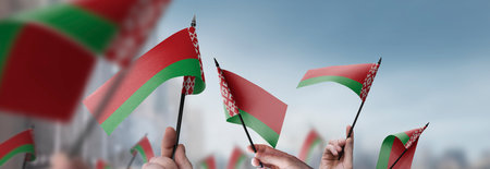 Belarus flags in their hands on a blurred urban backgroundの写真素材