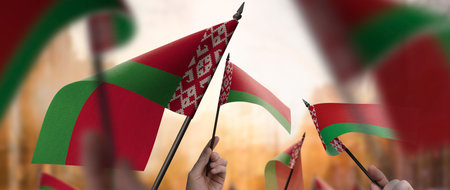 Belarus flags in their hands on a blurred urban backgroundの写真素材
