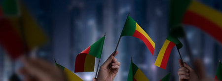 Benin flags in their hands on a blurred urban backgroundの写真素材