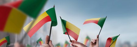 Benin flags in their hands on a blurred urban backgroundの写真素材