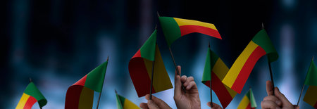 Benin flags in their hands on a blurred urban backgroundの写真素材