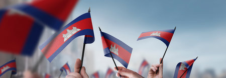 Cambodia flags in their hands on a blurred urban backgroundの写真素材